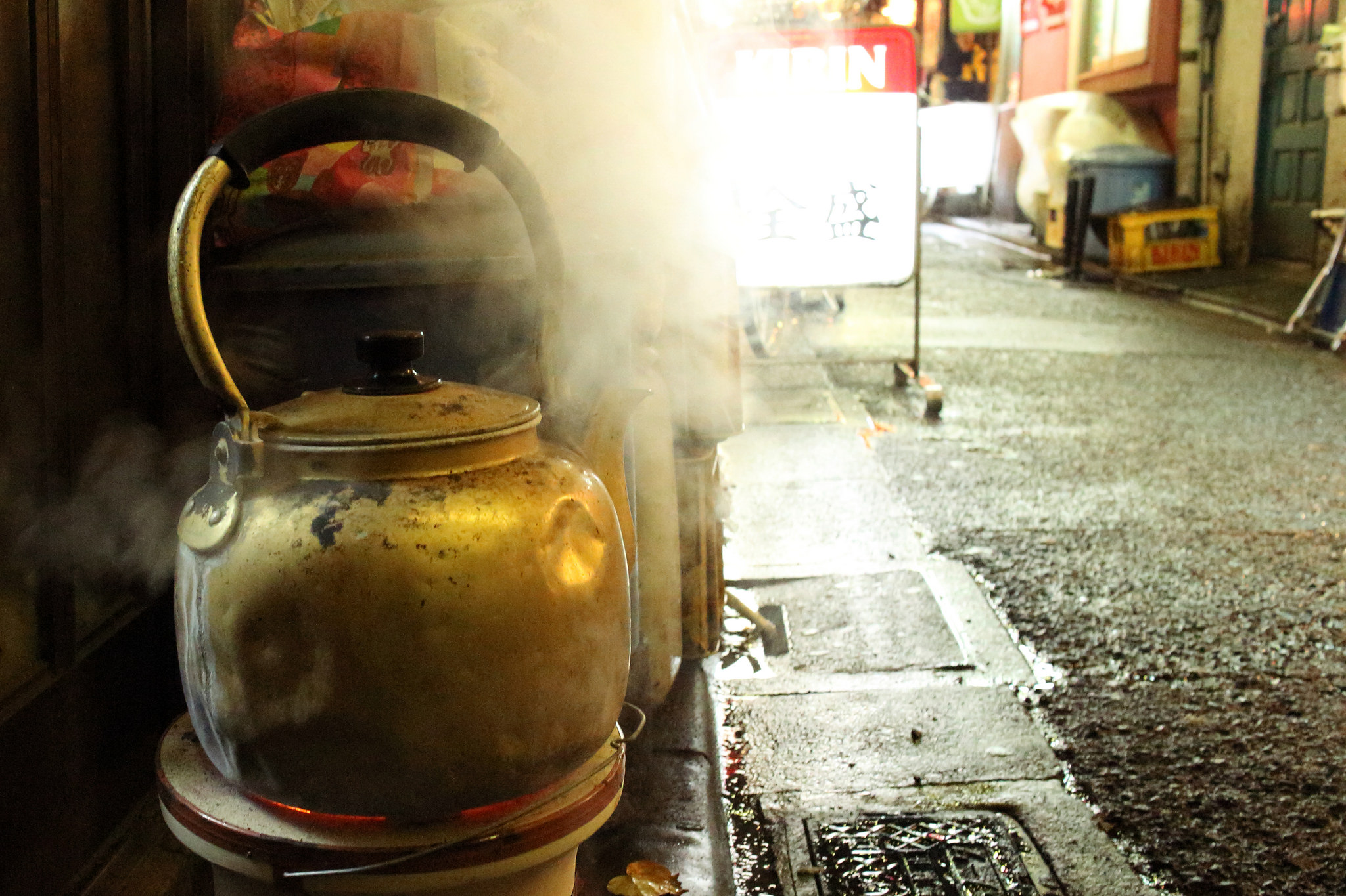 An old battered kettle boiling water on a side-street