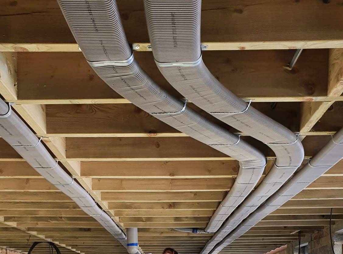 Flat 51mm semi-rigid ducting running pinned neatly to ceiling joists to prevent loss of room height