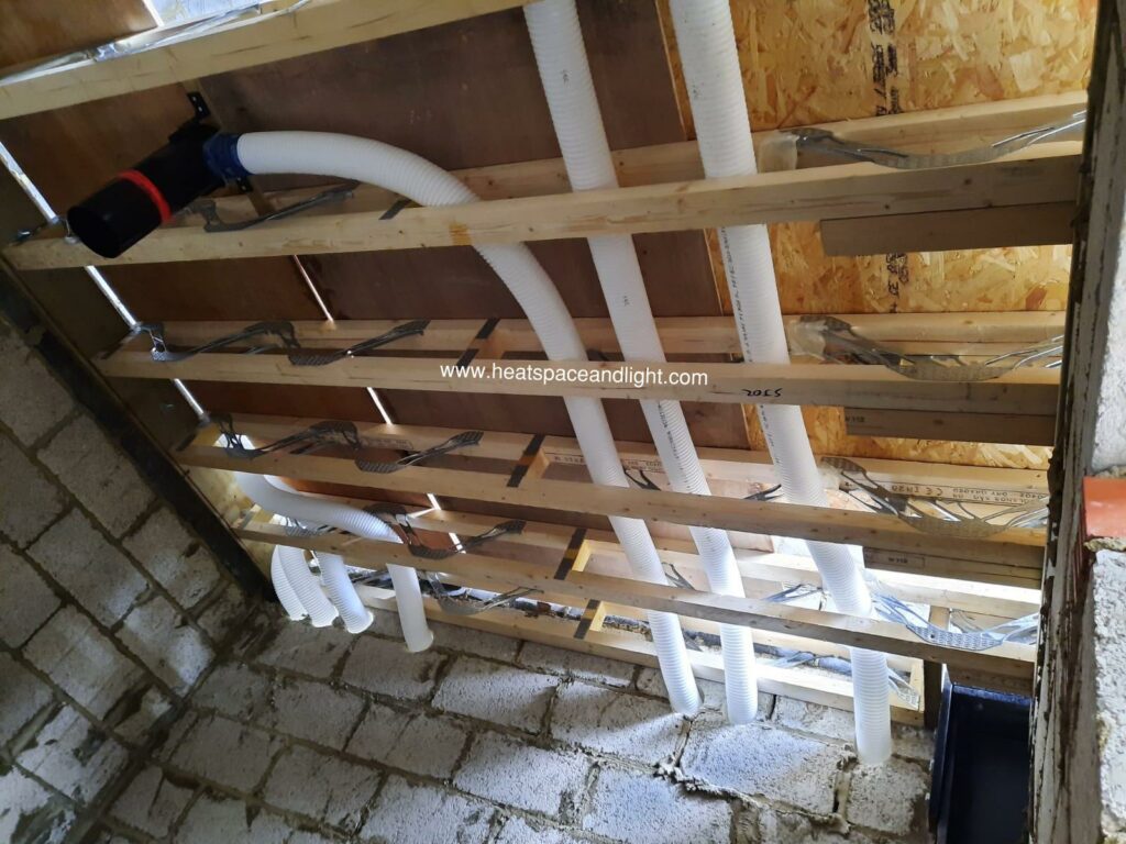 90mm semi-rigid ducting in webbed joists and passing through core-drilled blockwork wall for MVHR system