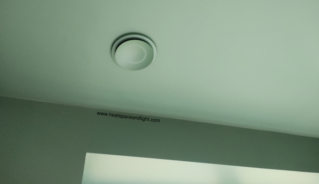 Close-up of the MVHR supply valve in the bedroom powder-coated the same colour as ceiling and walls