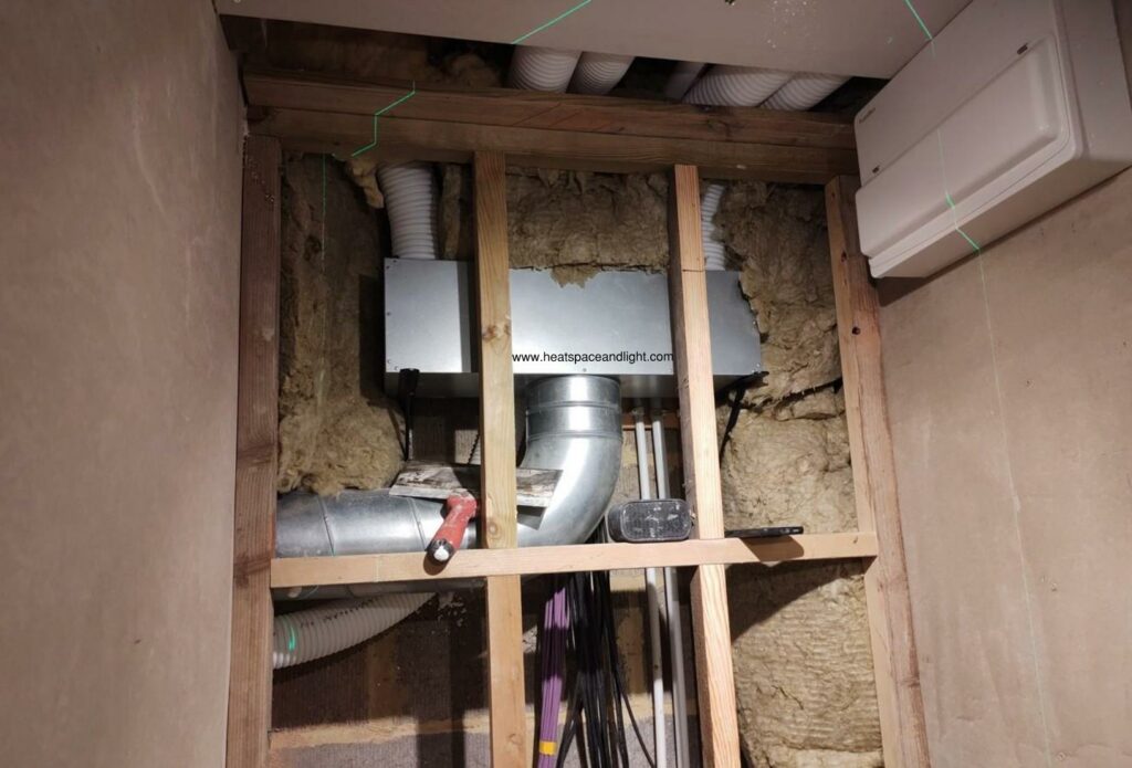 MVHR manifold hidden within cavity wall service riser behind WC